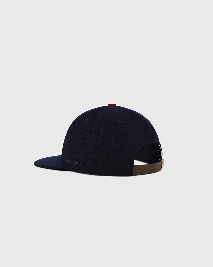 The St. Louis Cardinals 1963 MLB Authentic Wool Ballcap by Ebbets Field is shown from the back with a navy blue finish, curved brim, brown adjustable strap, and small red button. Part of the Decade of Change Collection. Light gray background.