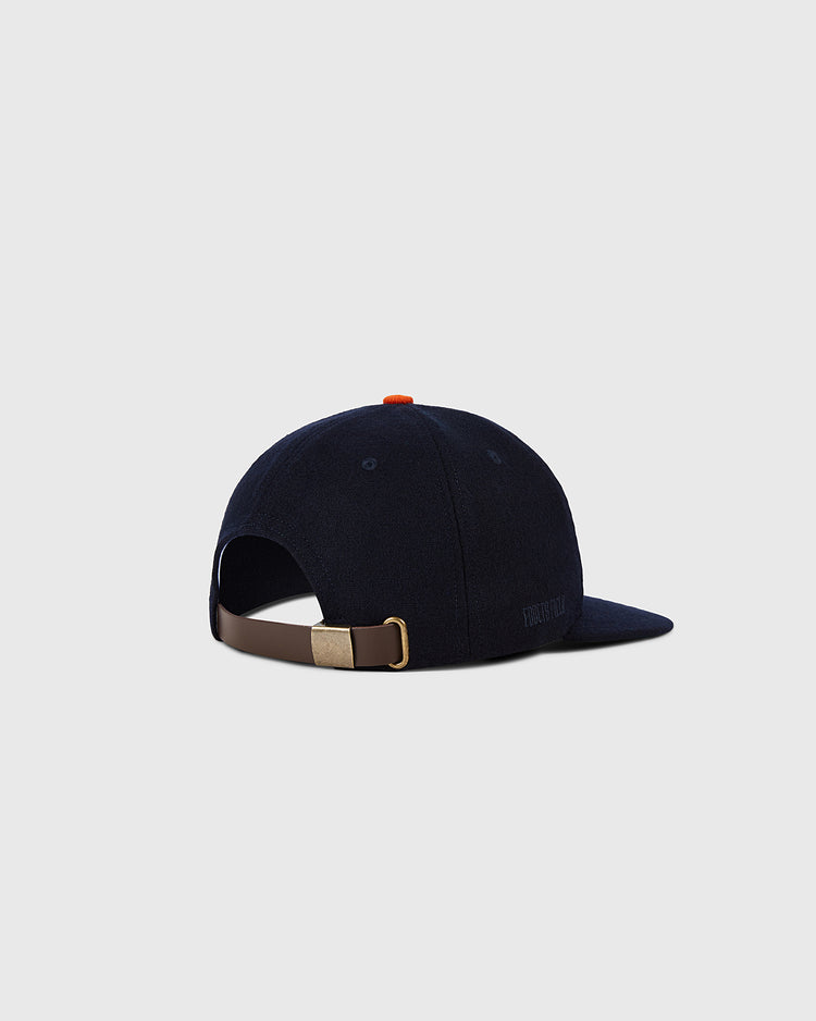 The Ebbets Field Houston Colt .45s 1962 MLB Authentic Wool Ballcap is navy blue with a brown adjustable strap, brass buckle, curved brim, and small orange top button, shown against a plain light gray background.