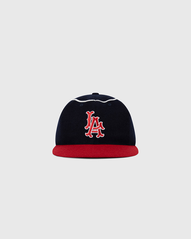 The Ebbets Field Los Angeles Angels 1961 MLB Authentic Wool Ballcap features navy blue wool, a red brim, and a white-and-red interlocking LA logo on the front, shown against a plain light gray background.