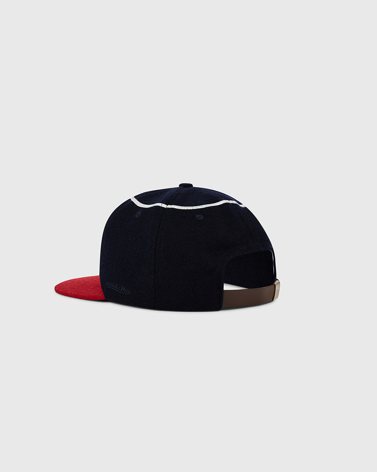 The Ebbets Field Los Angeles Angels 1961 MLB Authentic Wool Ballcap features dark blue wool, a red visor, white trim, and a brown adjustable strap, shown on a light gray background.