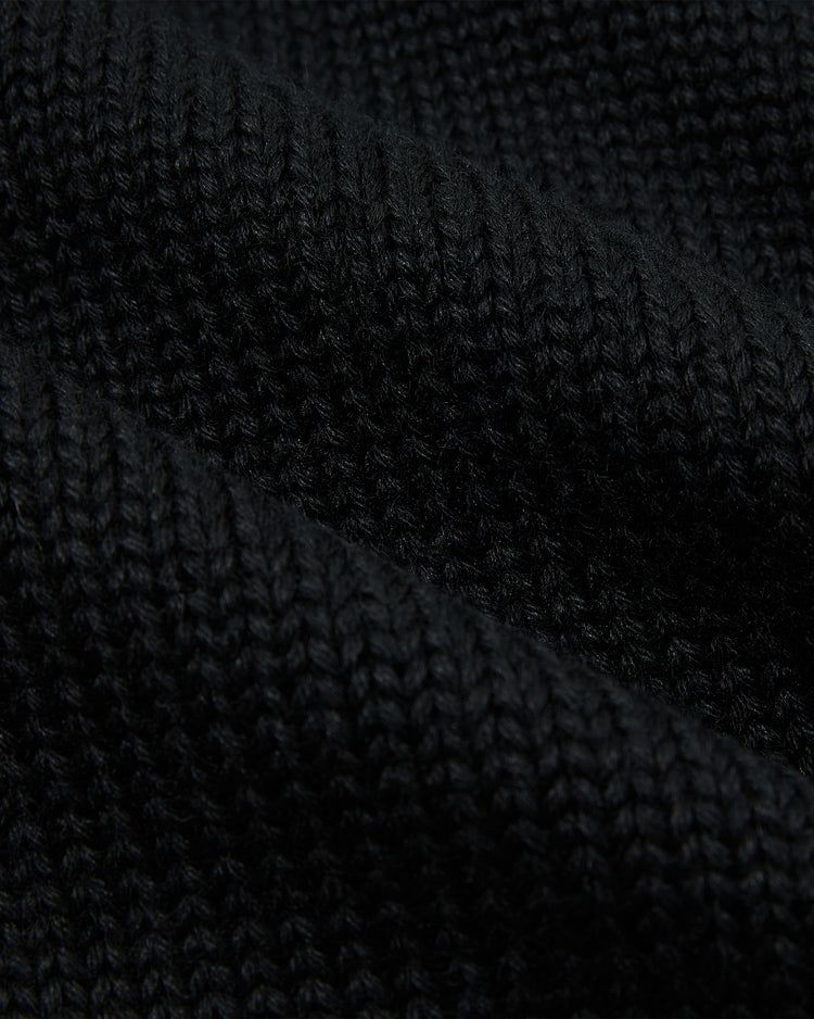 Close-up of black wool fabric from the EFF Baltimore Orioles 1901 Shawl Collar Sweater, highlighting its textured knit pattern with visible stitch rows and soft, slightly wavy folds.