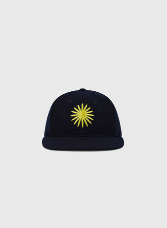 The EFF Darby Daisies 1932 Authentic Wool Ballcap features a navy blue design with a yellow sunburst embroidered on the front, inspired by the historic Hilldale club, shown on a plain light gray background.