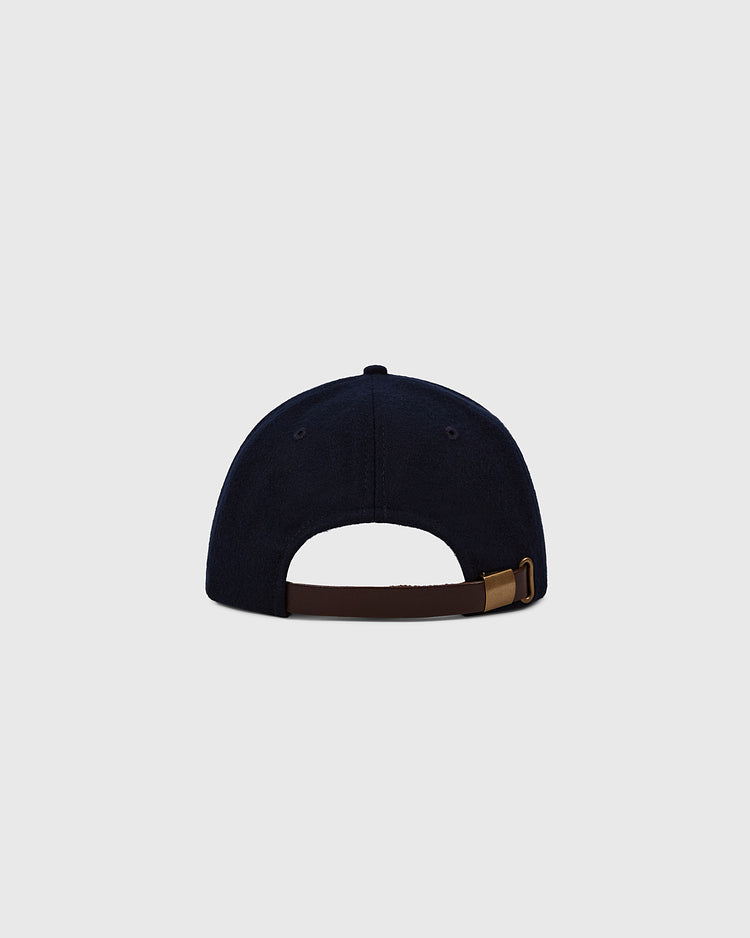 A Darby Daisies 1932 Authentic Wool Ballcap by EFF, shown from the back in navy blue with a brown adjustable strap and metal clasp, is set against a plain light gray background.