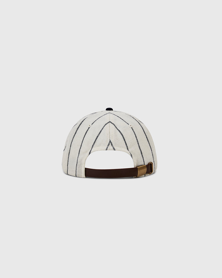 The Ebbets Felt 'E' Wool Pinstripe Ballcap by Ebbets Field is a vintage white cap with thin black stripes, made from wool broadcloth. Shown from the back, it has an adjustable brown strap with a brass buckle against a light gray background.