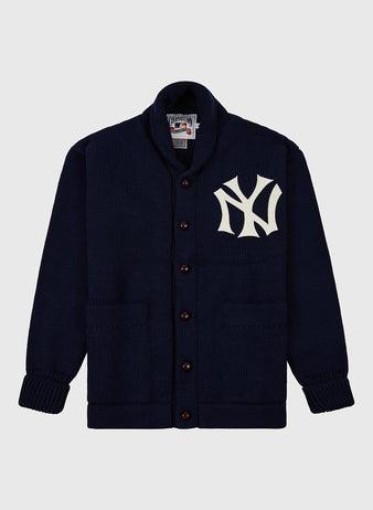 The Ebbets Field New York Yankees 1922 Wool Shawl Collar Sweater is navy blue with two front pockets, a large white NY logo on the left chest, and features a ribbed collar, cuffs, and hem for classic comfort.