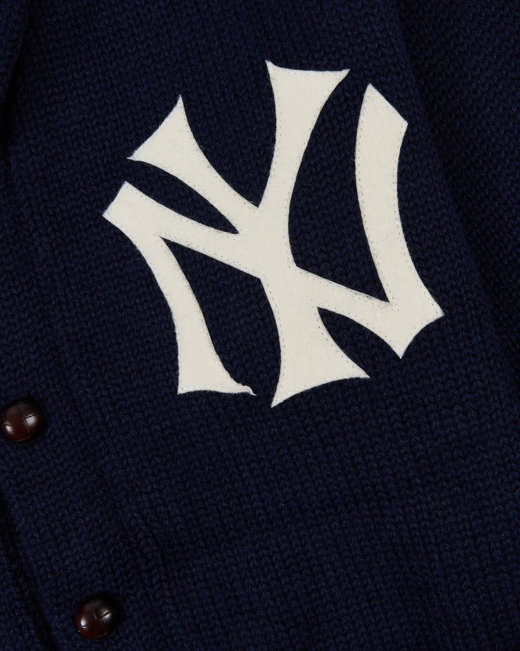 Close-up of the Ebbets Field New York Yankees 1922 Wool Shawl Collar Sweater in navy, featuring a white interlocking NY logo and brown buttons for a classic baseball history cardigan style.