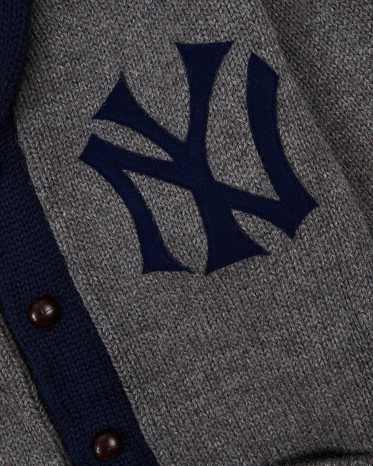 Close-up of the Ebbets Field New York Yankees 1922 Wool Shawl Collar Sweater, featuring a gray knit, dark blue NY logo, and dark buttons—an authentic reproduction of the classic 1922 Yankees sweater.