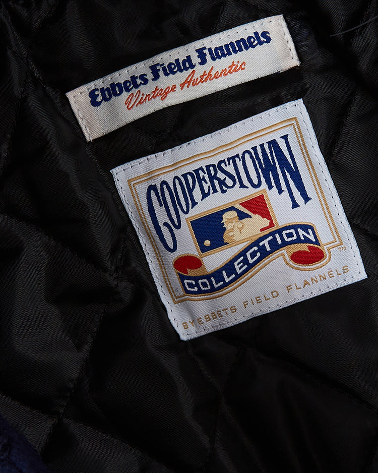 Close-up of two sewn labels on black quilted fabric from an authentic Chicago White Sox 1967 All Wool Varsity Jacket by EFF. The top label reads Ebbets Field Flannels Vintage Authentic; the lower shows Cooperstown Collection with a baseball.