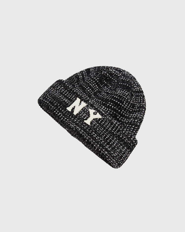 The Ebbets Field New York Black Yankees Felt Logo Ribbed Beanie is a black and white knit hat with a folded brim and bold NY felt logo, inspired by the Black Yankees, shown on a plain light gray background.