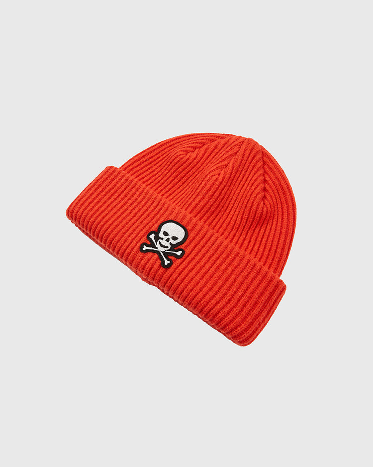 The Ebbets Field Sioux City Ghosts Embroidered Felt Ribbed Beanie is a bright orange knit hat with a folded cuff and a black-and-white skull and crossbones patch on the front, displayed on a plain light background.