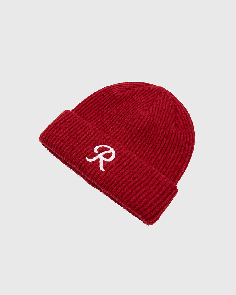 The Ebbets Field Seattle Rainiers Embroidered Logo Ribbed Beanie is a red knit hat with a folded brim, featuring a white 