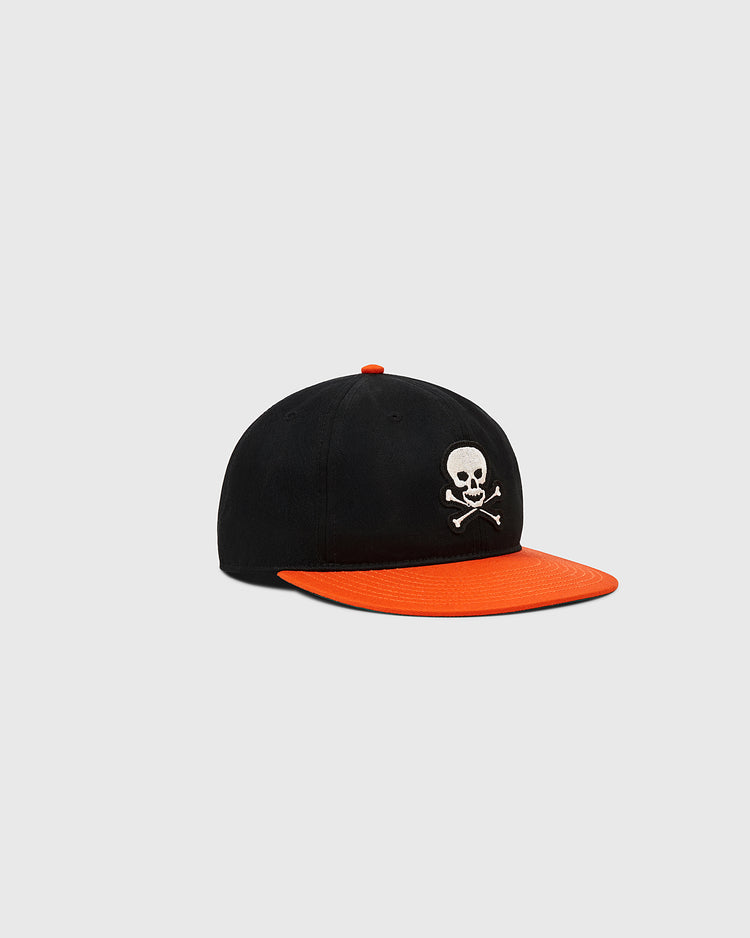 The Ebbets Field Sioux City Ghosts Cotton Twill Ballcap features a black crown, orange brim, and a white skull and crossbones on the front, paying tribute to the legendary team—shown against a plain light gray background.