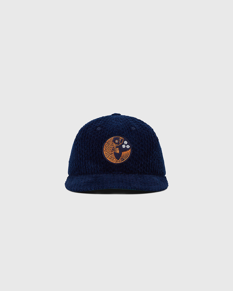 The Ebbets Field Hiroshima Carp Japanese Indigo Corduroy Ballcap, a navy blue hat with an embroidered gold fish on the front, is displayed against a plain light gray background.