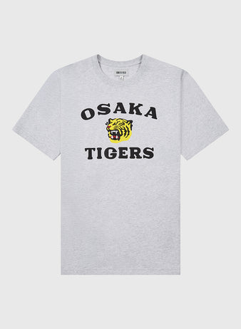 The Ebbets Field Osaka Tigers Short Sleeve Graphic Tee is a light gray t-shirt with bold black text and a yellow tiger head graphic on the front, inspired by Japanese baseball and Koshien Field legends.
