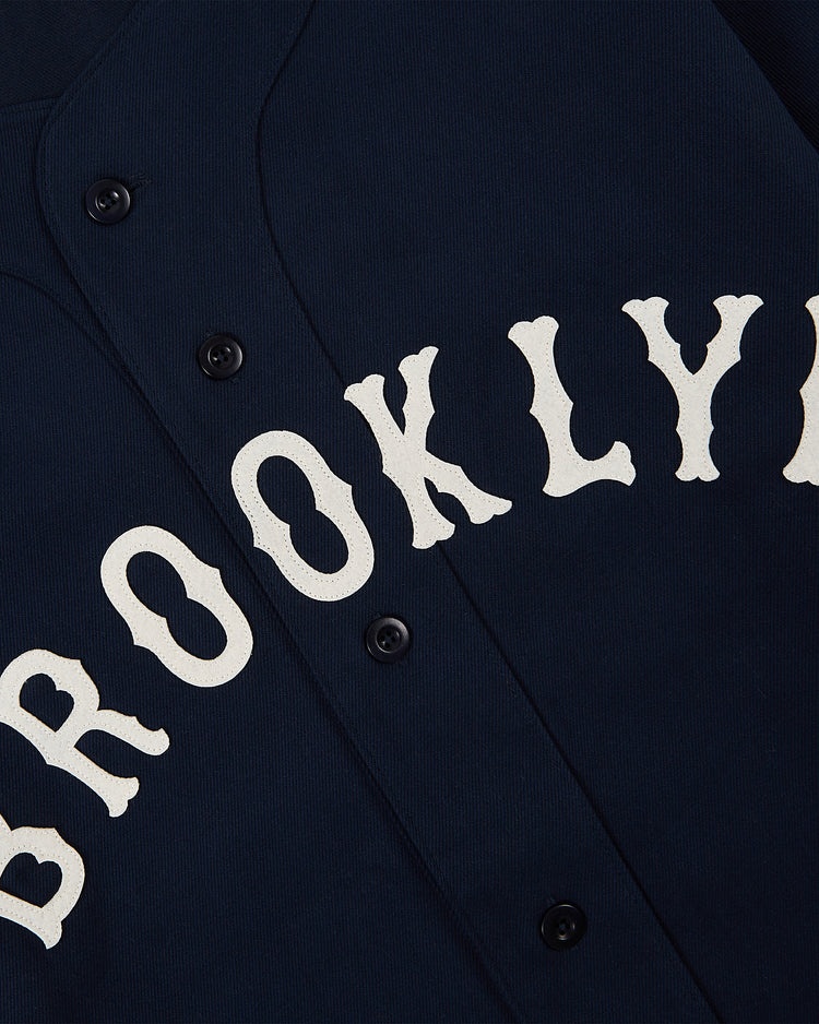 The Brooklyn Eagles Cotton Twill Baseball Jersey by Ebbets Field features navy cotton twill, large diagonal white 