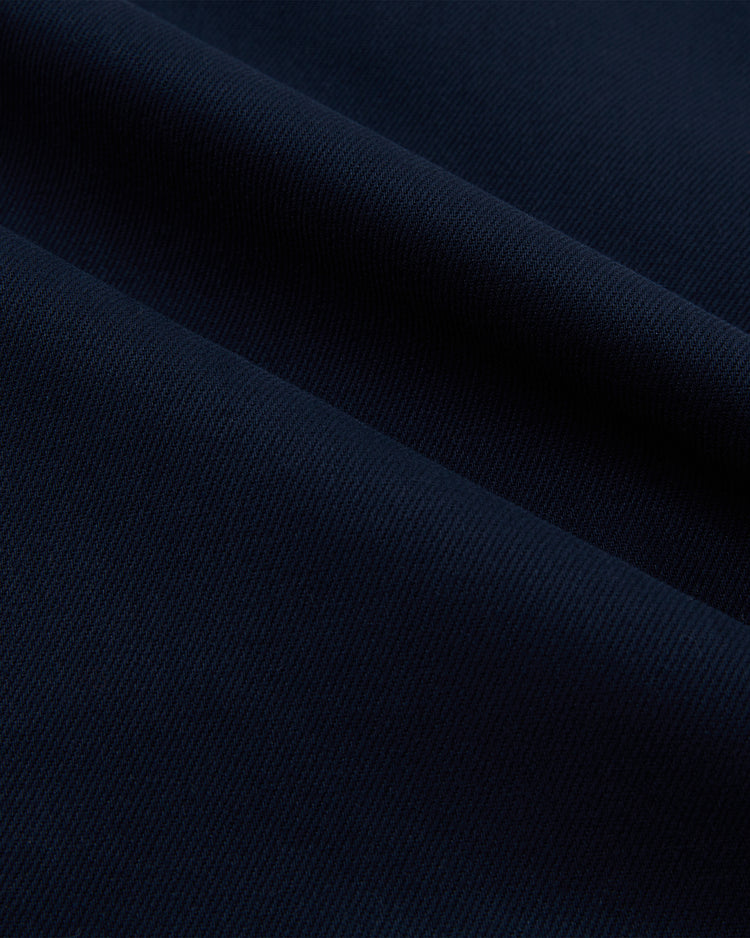 Close-up of dark blue cotton twill on the Brooklyn Eagles Baseball Jersey by Ebbets Field, featuring a fine ribbed texture and diagonal folds that recall classic Negro Leagues style, emphasizing its smooth surface and subtle pattern.