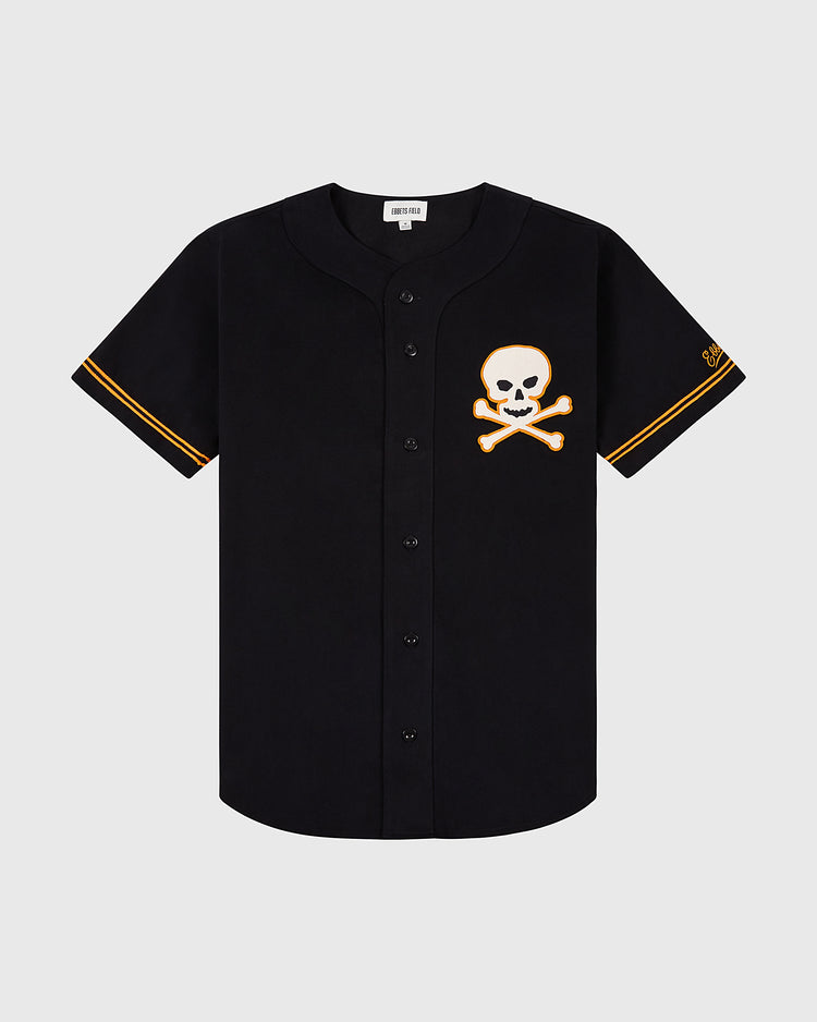 The Sioux City Ghosts Cotton Twill Baseball Jersey by Ebbets Field is a black short-sleeve jersey with orange sleeve trim and a skull-and-crossbones patch—perfect for fans and fast-pitch softball enthusiasts.