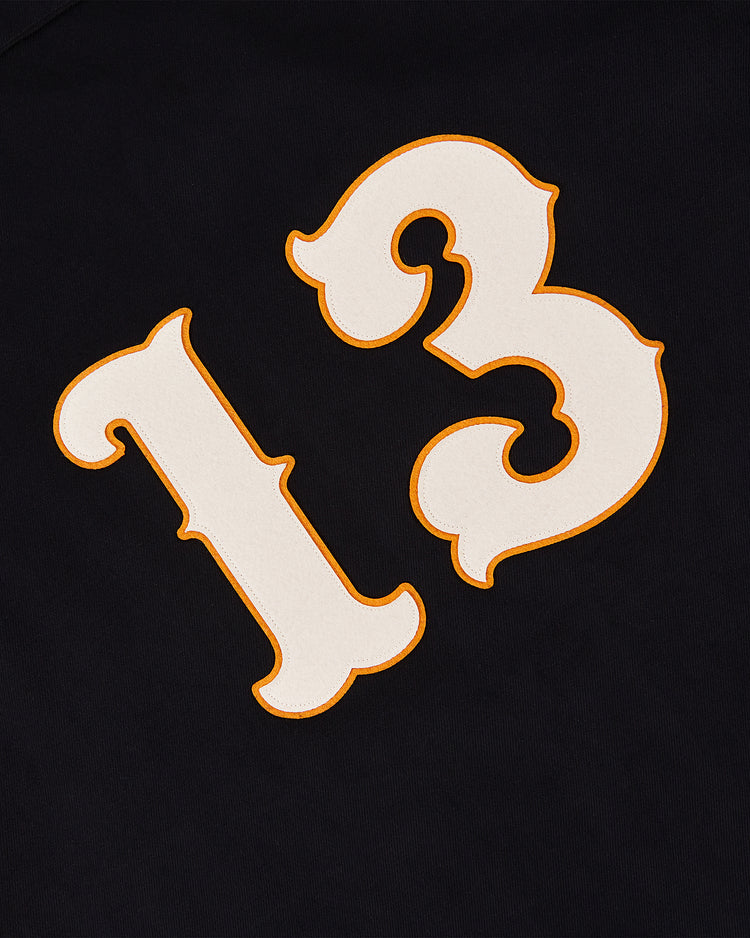 The Sioux City Ghosts Cotton Twill Baseball Jersey by Ebbets Field features a bold white number 13 with an orange outline on black fabric, capturing vintage baseball style.