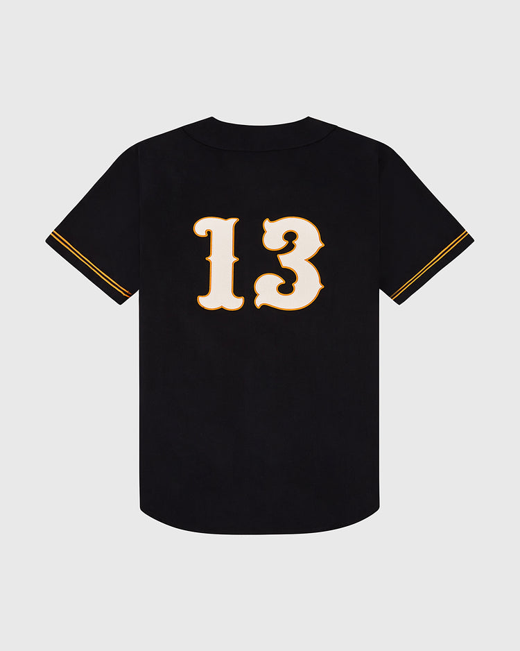 The Ebbets Field Sioux City Ghosts Cotton Twill Baseball Jersey features black fabric with gold sleeve accents and a bold white and gold number 13 on the back, displayed against a plain light gray background.