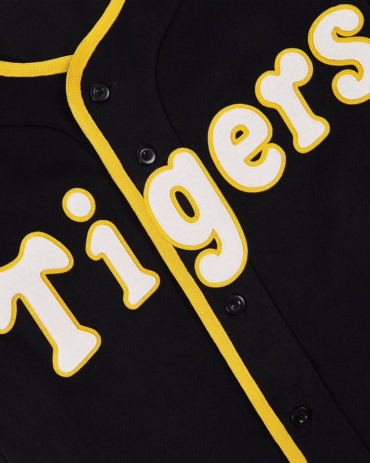 A close-up of the Ebbets Field Osaka Tigers Cotton Twill Baseball Jersey, featuring black cotton twill, yellow trim, and bold white and yellow 