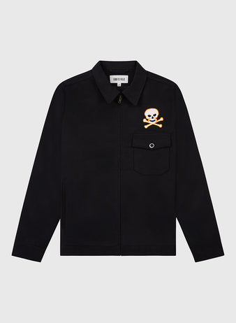 The Ebbets Field Sioux City Ghosts Cotton Grounds Crew Jacket is a black fast-pitch softball jacket with a front zipper, collar, and chest pocket. An orange and white skull and crossbones graphic appears above the left pocket on a plain white background.