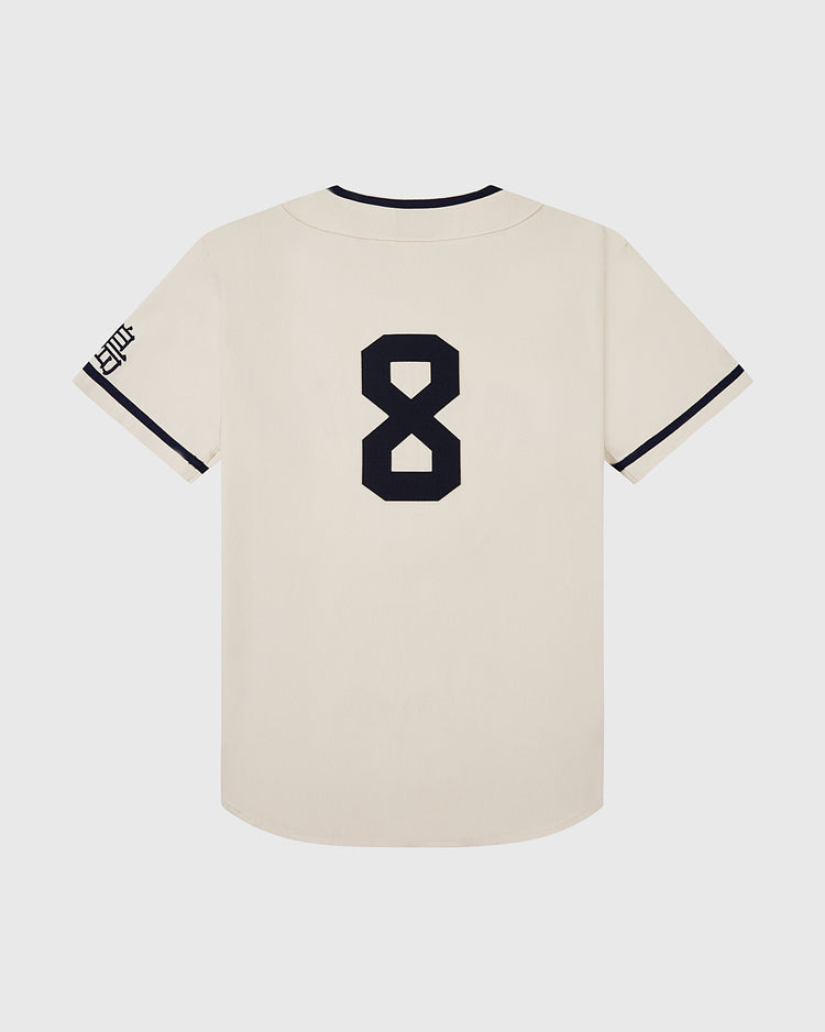 The Ebbets Field Hiroshima Carp Cotton Twill Baseball Jersey is cream-colored with black trim, a bold black number 8 on the back, and a subtle black logo on the left sleeve, crafted from cotton twill jersey.