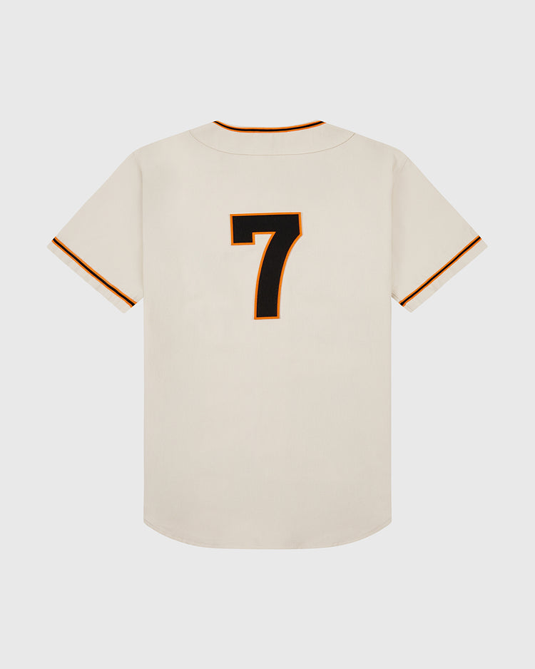 The Ebbets Field Tokyo Giants 1953 Cotton Twill Baseball Jersey features a cream color, short sleeves with black and orange trim, and a bold black and orange outlined number 7 on the back. Displayed against a plain white background.