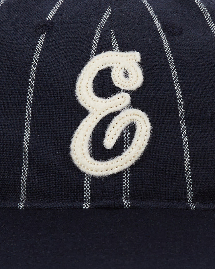 The Ebbets Field Ebbets Felt 'E' Wool Pinstripe Ballcap is a vintage navy wool cap with white pinstripes and a large cream cursive 