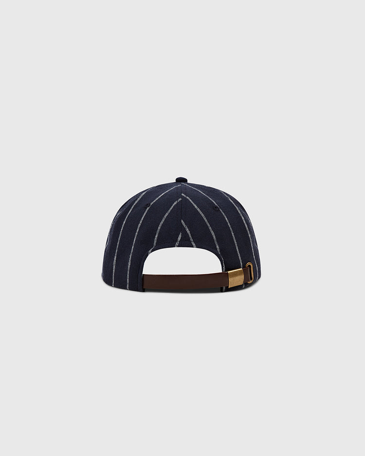 The Ebbets Field Ebbets Felt 'E' Wool Pinstripe Ballcap is a navy vintage cap with white vertical pinstripes, shown from the back with a brown adjustable strap and brass buckle, crafted from wool broadcloth against a light gray background.