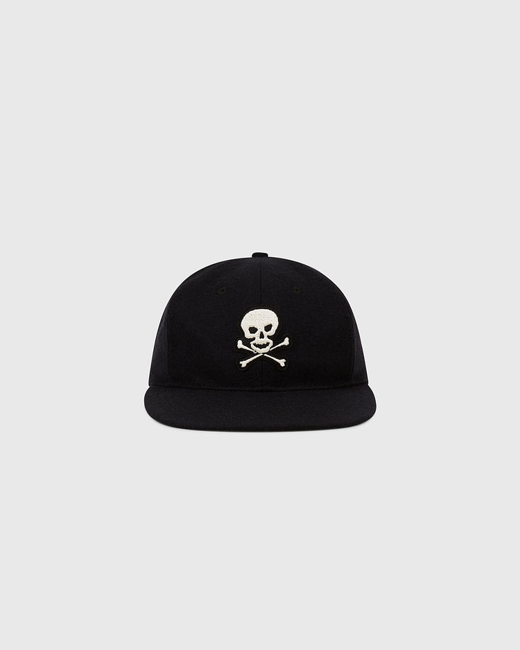The Ebbets Field Sioux City Ghosts Vintage Inspired Wool Ballcap is a black cap with a white skull and crossbones on the front, shown against a plain light gray background.