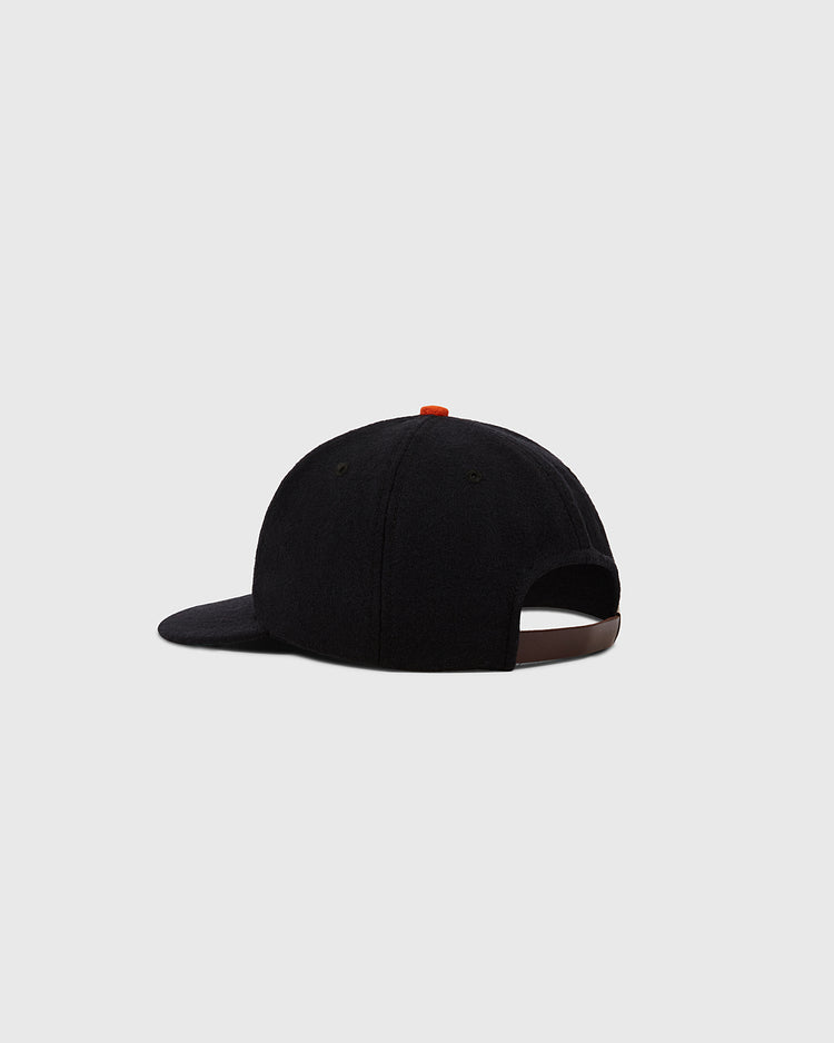 The Ebbets Field Tokyo Giants 1952 Authentic Wool Ballcap, shown from the back with a curved brim and adjustable brown strap with metal clasp, stands out against a plain light gray background.