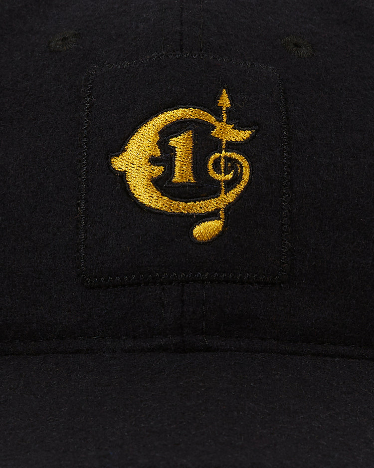 The Ebbets Field Tokyo Giants 1951 Authentic Wool Ballcap is a black wool cap with a gold embroidered design combining a currency symbol, the number 1, an arrow, and a musical note.