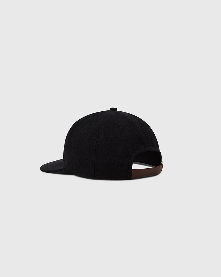 An Ebbets Field Tokyo Giants 1951 Authentic Wool Ballcap is seen from the back and slightly to the side, showcasing its adjustable brown strap against a plain light gray background.