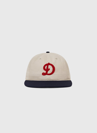 The Ebbets Field Detroit Stars Cotton Twill Ballcap is a beige cap with a navy blue brim and red D, inspired by the 1920 team, shown on a plain light gray background.