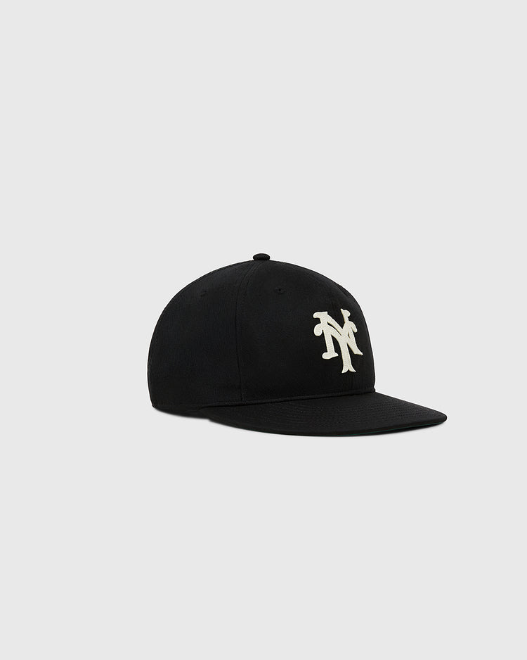 The Ebbets Field New York Cubans Cotton Twill Ballcap is a black flat-brim cap with a bold white interlocking NY logo on the front, shown on a plain light gray background.