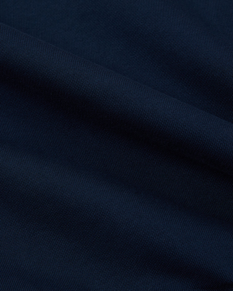 A close-up of dark blue heavyweight cotton terry fabric with diagonal weave and soft folds, highlighting the texture and shadows—perfect for the Ebbets Field Hiroshima Carp Full-Zip Hoodie.