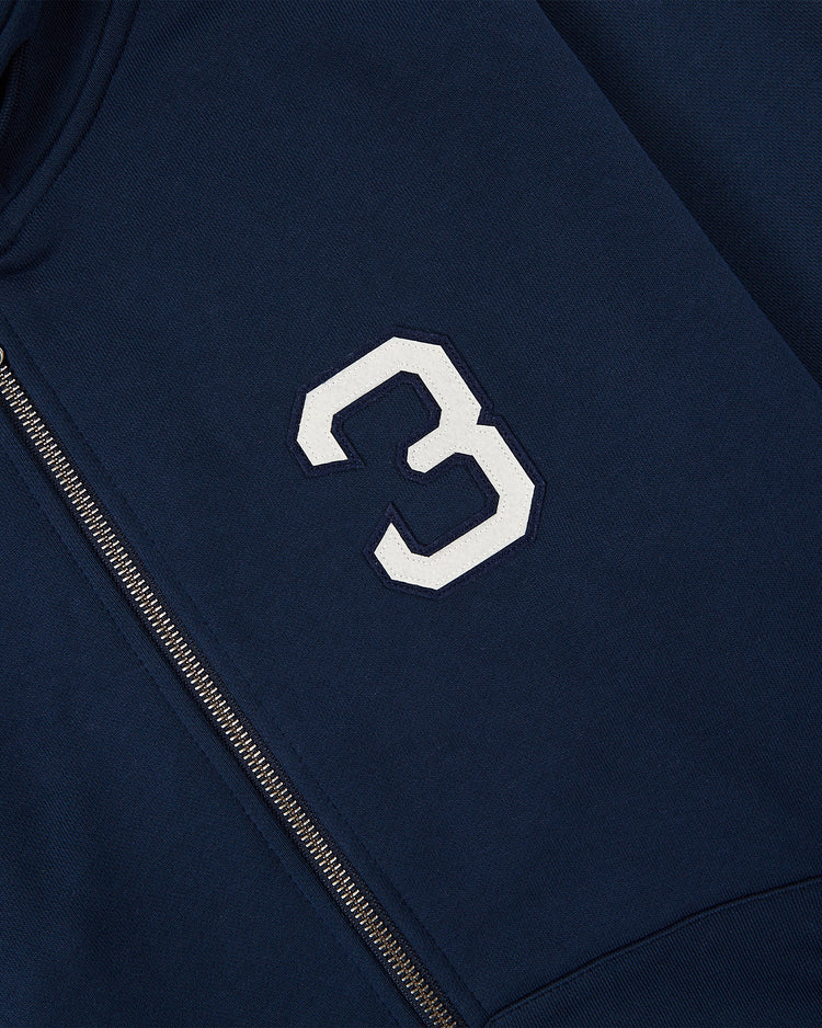 Close-up of the Ebbets Field Babe Ruth Heavyweight Cotton Terry Full-Zip Hoodie in navy, featuring a white number 3 patch inspired by classic baseball legend apparel.