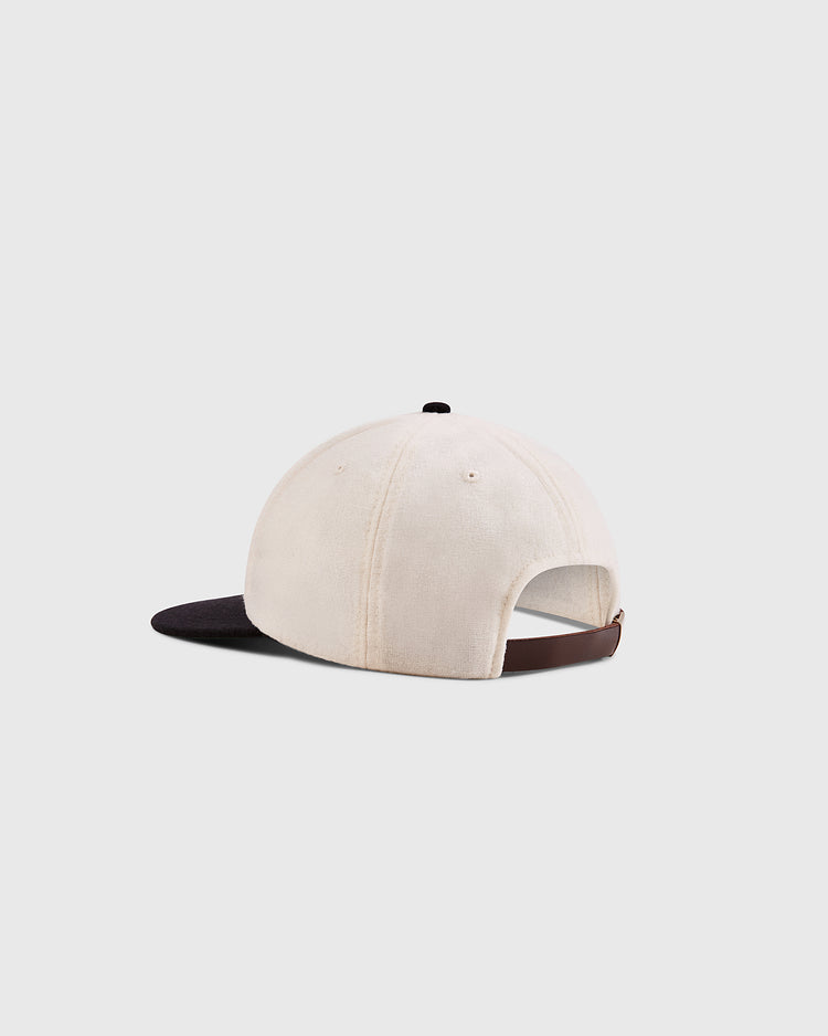 The Ebbets Field Babe Ruth Bustin' Babes Authentic Wool Ballcap features a cream crown, black brim, and brown adjustable strap, inspired by Babe Ruth’s barnstorming era, shown on a plain light gray background.