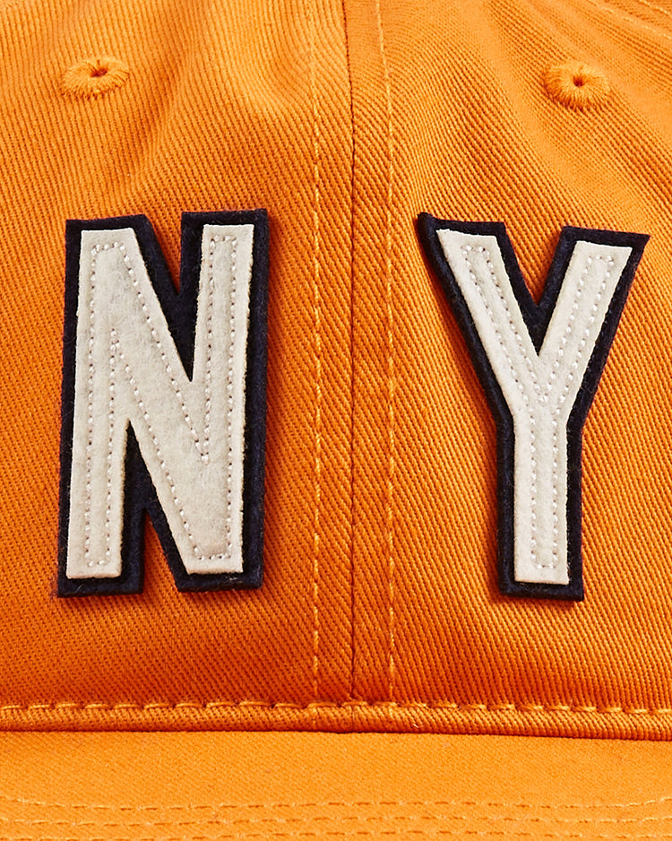 Close-up of an orange Ebbets Field New York 1939 World's Fair Cotton Twill Ballcap, featuring large white NY letters outlined in black stitched on the front.