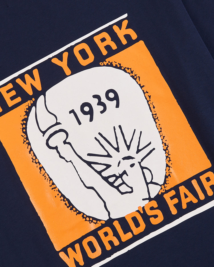 The Ebbets Field New York 1939 World's Fair Short Sleeve Graphic Tee features a navy and orange design with the Statue of Liberty, “New York World’s Fair,” and 1939—celebrating the iconic event in classic style.