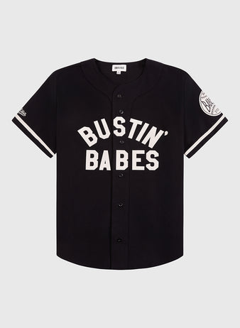 The Ebbets Field Babe Ruth Bustin' Babes Cotton Twill Baseball Jersey is black with white trim, bold BUSTIN BABES lettering on the front, and a left sleeve patch honoring the 1927 barnstorming tour.