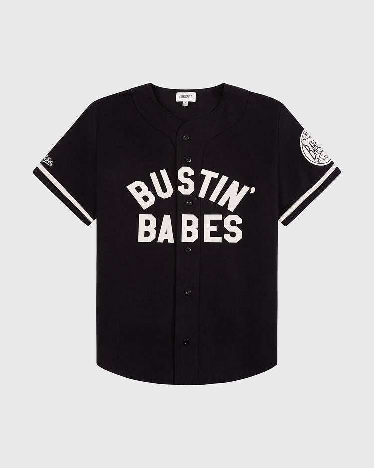 The Ebbets Field Babe Ruth Bustin' Babes Cotton Twill Baseball Jersey is black with white trim, bold BUSTIN BABES lettering on the front, and a left sleeve patch honoring the 1927 barnstorming tour.