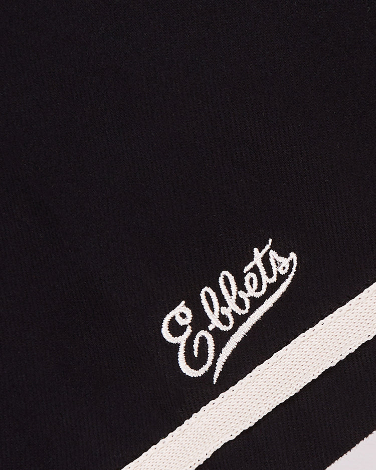 The Ebbets Field Babe Ruth Bustin' Babes Cotton Twill Baseball Jersey features black fabric with “Ebbets” embroidered in white cursive above two white stripes, echoing the 1927 barnstorming Babe Ruth and Bustin’ Babes replica styles.