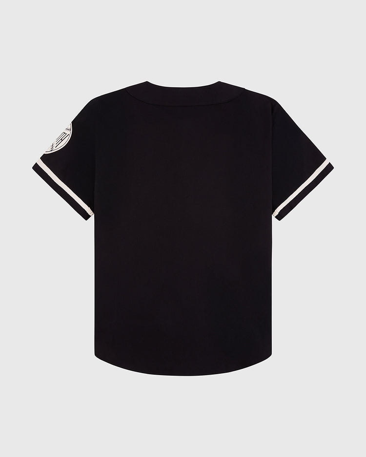 The Ebbets Field Babe Ruth Bustin' Babes Cotton Twill Baseball Jersey features black short sleeves with white stripe cuffs and a white circular patch on the left sleeve, shown from the back against a plain light background.