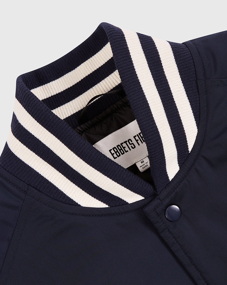 Close-up of the Ebbets Field New York 1939 World's Fair Satin Varsity Jacket, featuring a navy blue body, ribbed collar with white and dark blue stripes, snap button closure, and EBBETS FIELD label inside.