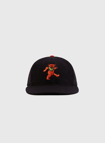 The Ebbets Field Grateful Dead Dancing Bear Wool Ballcap in black features an orange embroidered dancing bear on the front, shown against a light gray background.