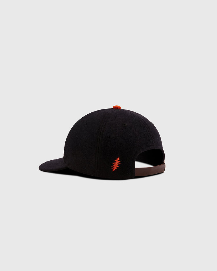 The Ebbets Field Grateful Dead Dancing Bear Wool Ballcap, seen from the back, features a small red lightning bolt on the side, an adjustable strap, and a subtle tribute to the legendary band against a plain gray background.