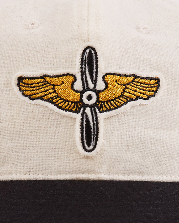 Close-up of the Ebbets Field Mystery Caps of Mexico – Aviacion 1917 Authentic Wool Ballcap, featuring an embroidered gold wing and propeller emblem on cream wool—a unique collector’s piece honoring Mexican baseball history.