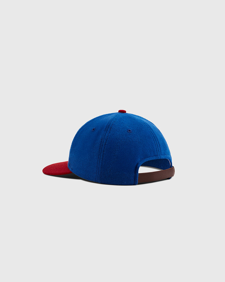 The Ebbets Field Sankei Atoms 1966 Vintage Inspired Wool Ballcap features blue wool, a red brim, an adjustable brown strap at the back, and is inspired by Astro Boy memorabilia, shown against a light gray background.