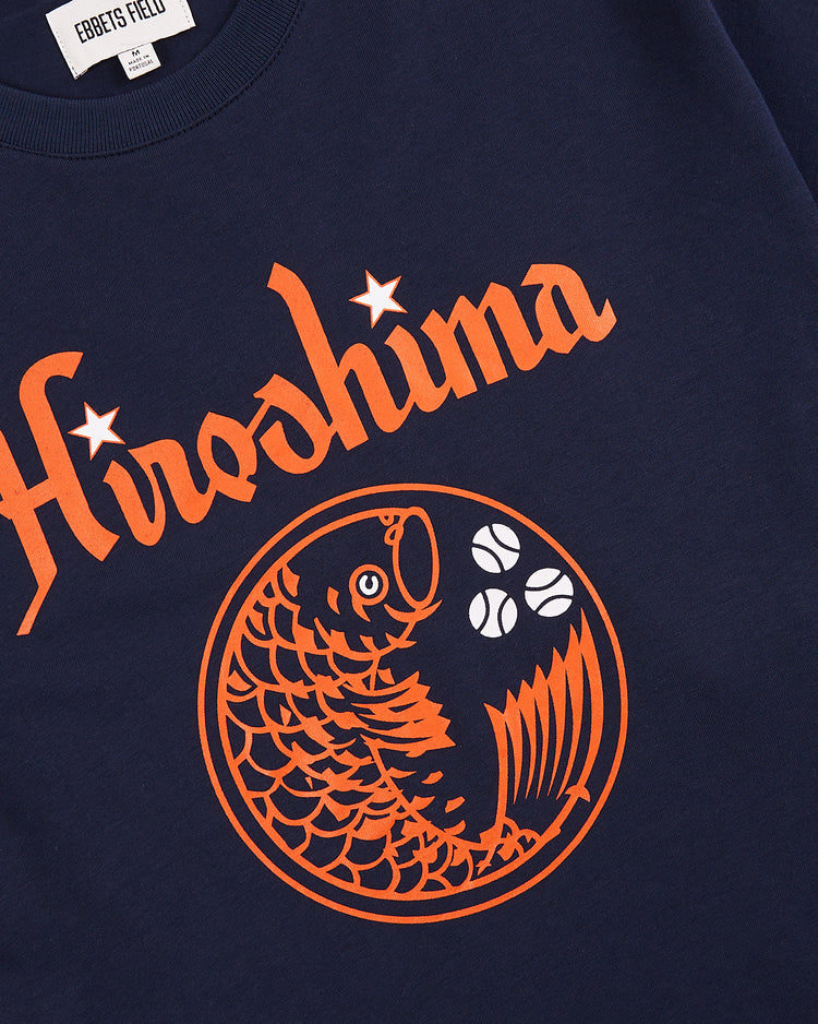 The Hiroshima Carp Short Sleeve Graphic Tee by Ebbets Field features “Hiroshima” in orange script above an orange koi fish and three baseballs. Ideal for Japanese baseball shirt collectors.